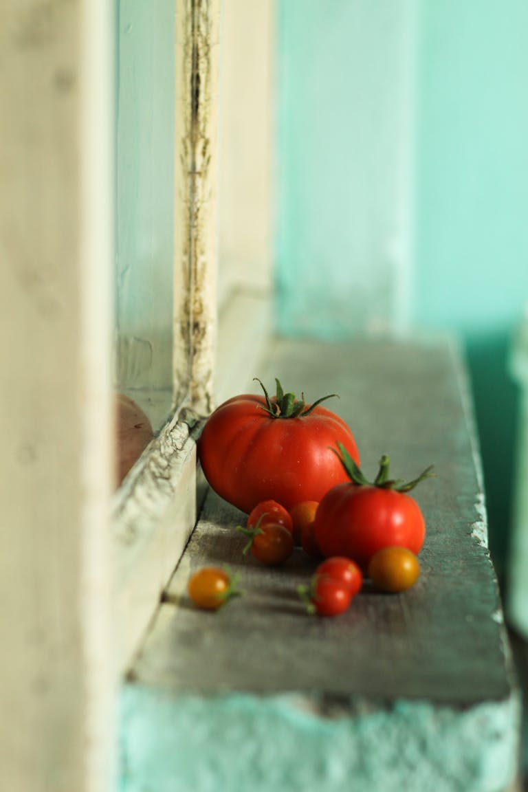 A collection of ripe red tomatoes resting on a vintage windowsill with rustic charm.