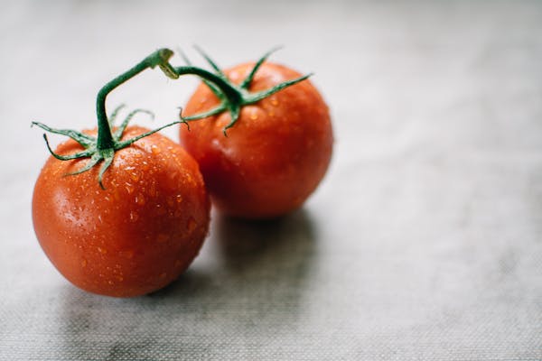 Close-up of fresh juicy tomatoes with water droplets on a textured surface, perfect for healthy living.